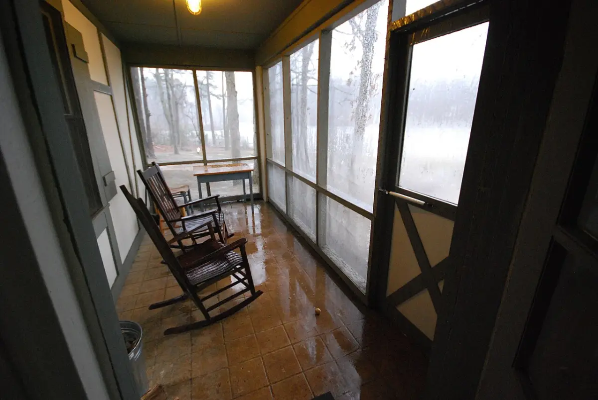 Rocking chairs on the porch of a wooden cabin on a rainy day