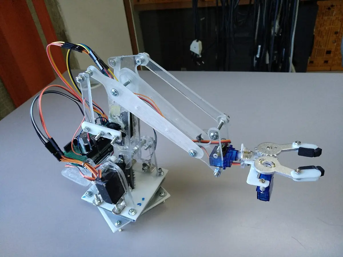 A small home-built robot arm with a gripper, made of clear plastic and small motors